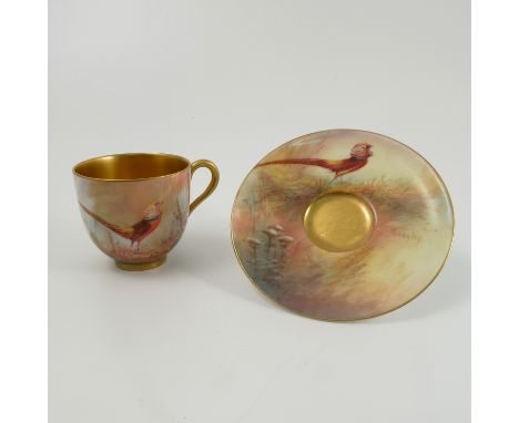 A Royal Worcester cabinet cup and saucer, the exterior of the cup and the saucer decorated with an Aetheatic pheasant in land