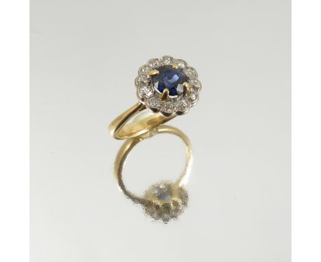 A sapphire and diamond cluster ring, the round cut stone, 6mm diameter, enclosed by twelve old single cuts totalling approxim