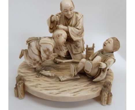 A late 19th / early 20thC Japanese ivory figural group depicting a father and two sons playing, with carved floral base and l