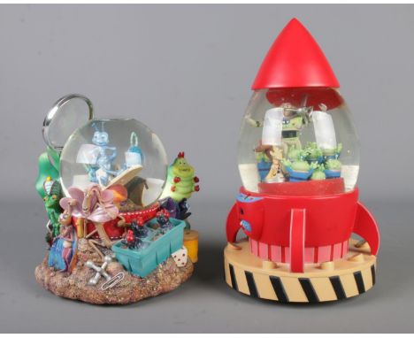 A boxed Toy Story rocket snow globe with a Bugs Life snow globe.  Both globes have slight damage