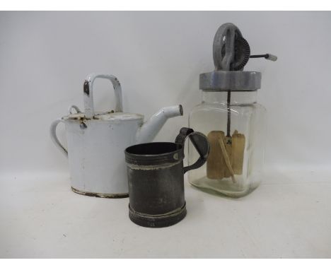 A large glass butter churn, an enamel watering can and a measure.