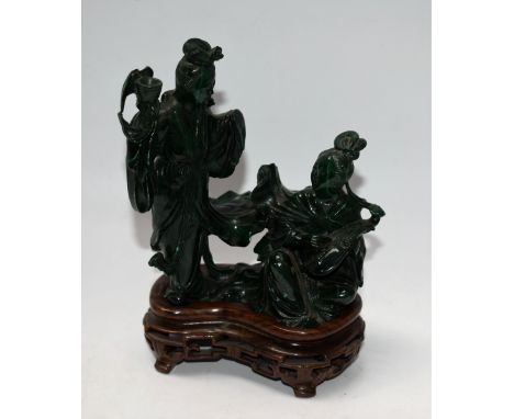 A Chinese malachite carving, of two courtly ladies, one stands proffering libation, the other seated playing a pipe, each wit