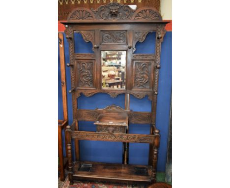 A Victorian oak hall stand, shaped cresting centred by a carved and applied Green Man flanked by scrolling foliage and flower