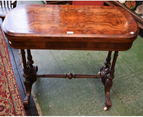 A Victorian walnut and marquetry card table, hinged stadium shaped top inlaid with stylised flowers and foliage enclosing a b