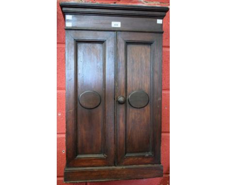 An early-mid 20th century mahogany wall hanging cabinet, outswept cornice above a pair of panel doors applied with elliptical