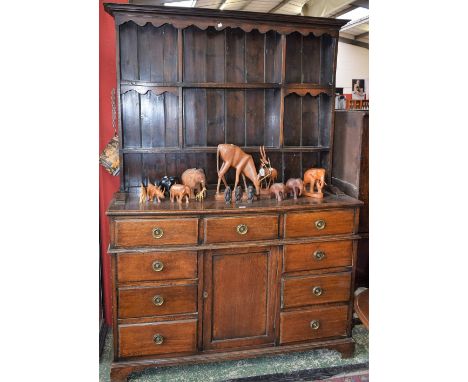 An early 20th century oak farmhouse dresser, outswept cornice above a shaped apron and an arrangement of segmented plate rack