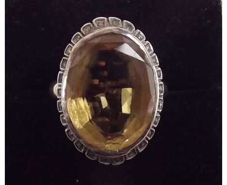 A yellow metal ring set yellow stone in white metal surround 