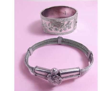 A Victorian silver hinged bangle with engraved decoration and an Eastern white metal bracelet 