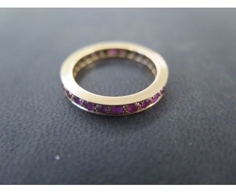 An 18ct hallmarked yellow gold ruby eternity ring size R/S - approx weight 5 grams - abrasions to stones, minor wear to ring
