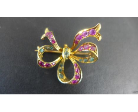A 15ct yellow gold ruby and emerald ribbon bow brooch 25mm x 30mm - set with 12 emeralds and 17 rubies - approx weight 6 gram