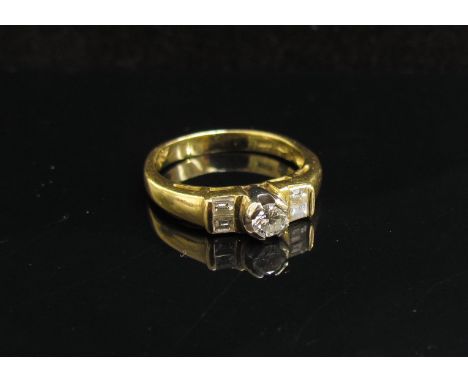 A gold ring set with central diamond flanked by baguette cut diamonds, stamped 750. Size K, 3.6g