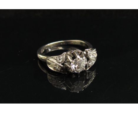 A white gold ring the central diamond flanked by diamond set shoulders, stamped 18ct. Size J/K, 3.4g