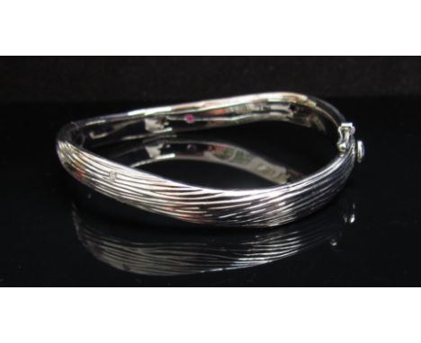 An 18ct white gold wavy bangle with diamond set sweetheart clasp and single diamond to front of bangle, 22g