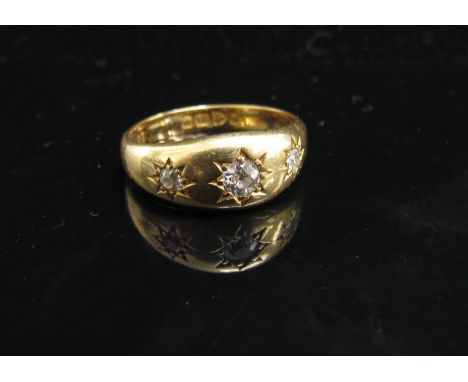 An 18ct gold ring with three diamonds in star settings. Size N/O, 4.9g