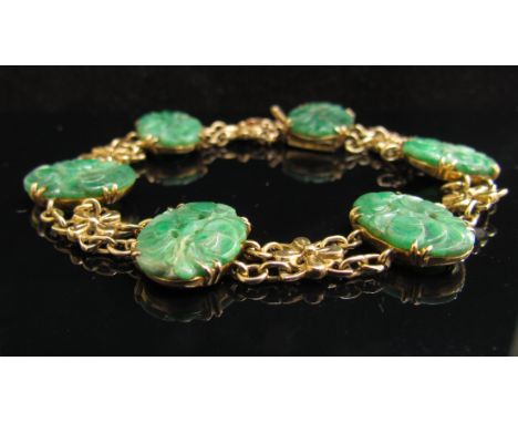 A gold bracelet with six carved oval jade panels stamped 9ct, 18.1g