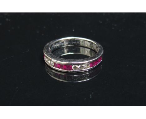 An 18ct white gold ruby and diamond half hoop in channel setting. Size M, 3.9g
