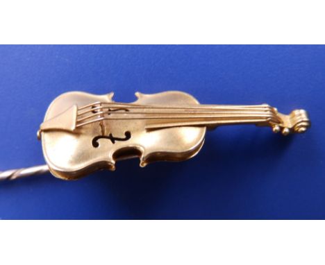 A gold coloured stick set with a miniature model of a violin