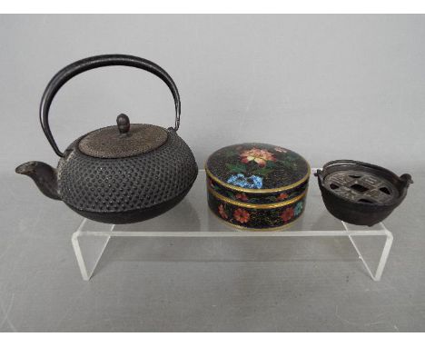 A cloisonné lidded trinket box of circular form, decorated with flowers against a black ground, a cast iron tetsubin and simi