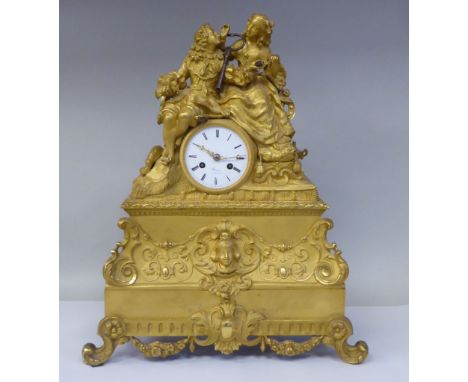 A 19thC French gilt metal cased mantel clock, featuring a seated couple, on a draped cushion, the deep plinth cast with a mas