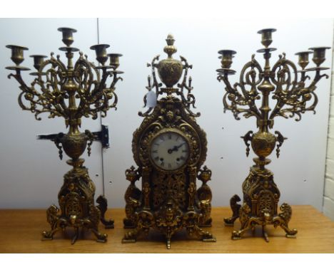 A mid 20thC mantel clock, the brass case profusely decorated in Empire style; the 8 day movement faced by an enamelled Roman 