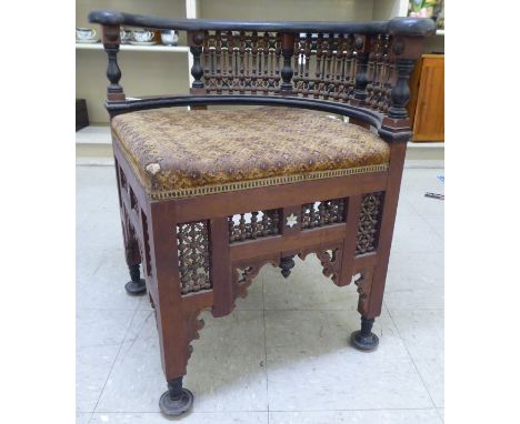 A late 19thC Moorish mother-of-pearl inlaid fruitwood corner chair with an upholstered seat, raised on turned legs 