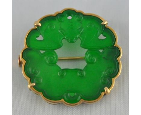 A Chinese yellow gold and green jade brooch, having an apple green jade disc&nbsp;pierced and carved as a bat above stylised 