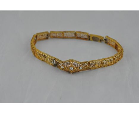A yellow metal and seed pearl bracelet, having octagonal pierced panel set central seed pearl within lozenge shaped mount wit