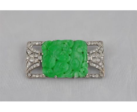 An Art Deco white metal, diamond and carved jade pendant, having central apple green jade panel carved and pierced with dog o