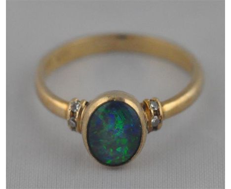 A 14ct. yellow gold and green opal set ring, having oval green opal cabochon in rub over setting flanked by three channel set