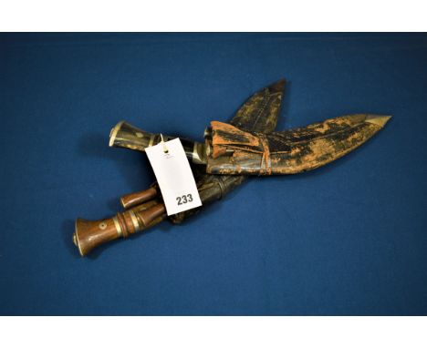 Two Kukri with leather scabbards and accompanying knives probably late 19th / early 20th century, the first with horn handle 