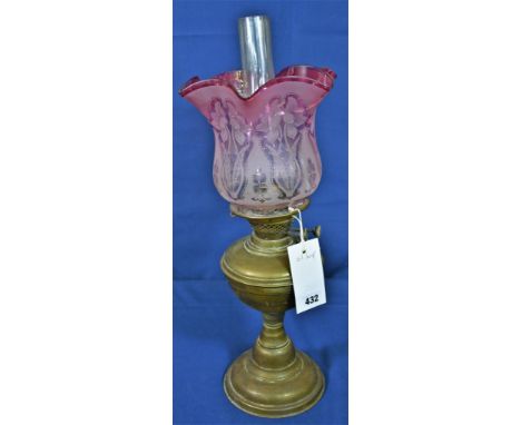 An Antique brass oil lamp with etched ruby glass floral decorated shade. 
