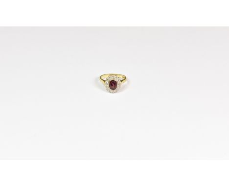 An 18ct gold, ruby and diamond cluster ring the oval cut ruby within a scalloped border of brilliant cut diamonds, Birmingham