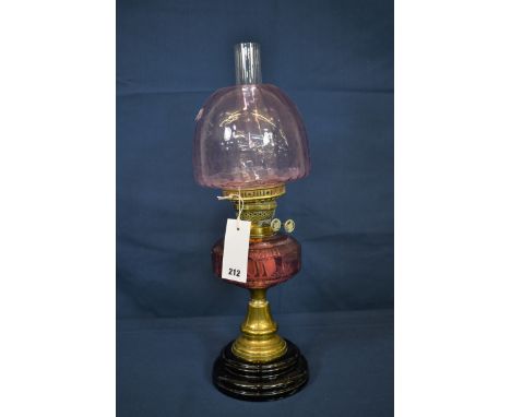 An antique cranberry coloured glass and brass oil lamp. 