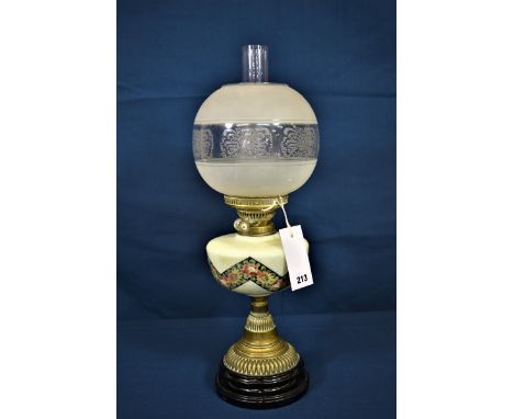 An antique brass oil lamp with etched glass globe and floral decoration. 