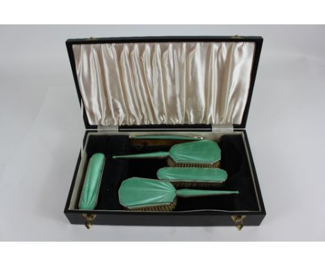 A cased five piece silver and green guilloche enamel Art Deco dressing table set, Birmingham 1930, comprising two hair brushe