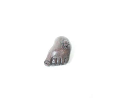 A carved wooden netsuke of a foot and a spider