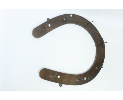 A 1930/40's oak hanging rack in the form of a horse shoe, with original ceramic casters