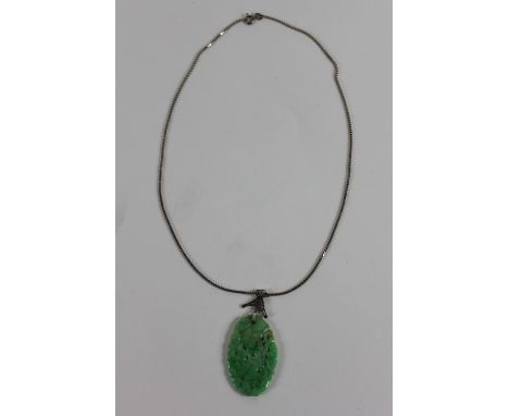A jade pendant, the oval carved and pierced plaque 4.2 cm long, the fancy white metal bale stamped '9ct'; on a box link chain