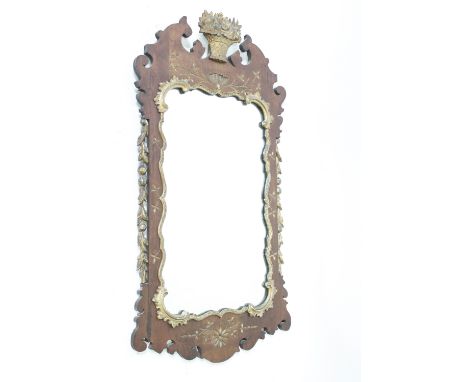 A 20th century shaped mahogany framed mirror with a gilded outline and a finial of flowers, 110cm high, 53cm wide