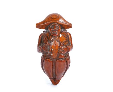 Late 18th Century treen figural coquilla nut snuff box, carved as a crouching soldier with a bicorn hat, his right hand clutc