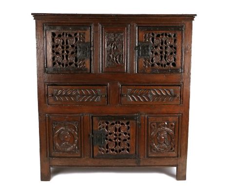 
A magnificent and rare Henry VIII joined oak aumbry or livery cupboard, circa 1520, the front following a traditional arrang