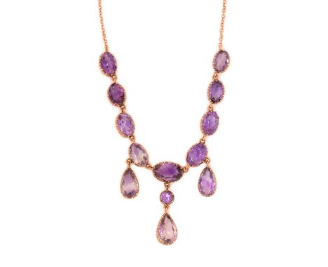 An early 20th Century amethyst fringe necklace, with three pear-cut drops below graduated oval facet cut stones, in claw moun
