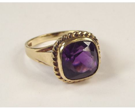 GOLD RING. A 9ct. gold ring, set a square cut dark amethyst within a rope twist mount. Size M/N.