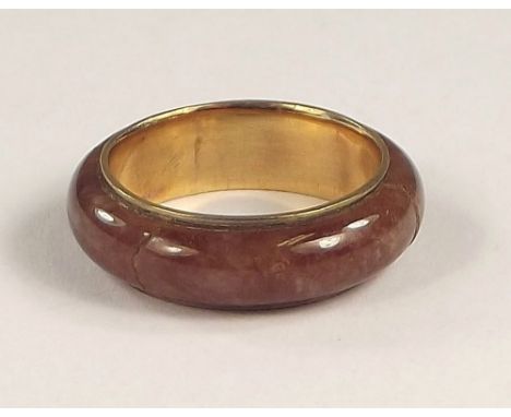 JADE RING. A red/brown jade ring lined with yellow metal. Approx. 3.9g.
