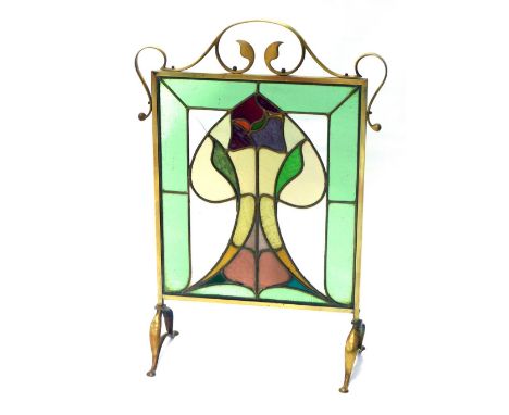 An early 20thC brass Art Nouveau fire screen, with lotus flower coloured glass centre, and scroll outline, on paw feet, 85cm 