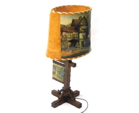 An oak table lamp, with leather shade transfer printed with tavern scene marked Bennet, on a carved stem and X shaped feet, 8