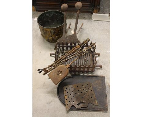 A brass coal bucket with embossed armorial and lion mask ring handles and a group of fire irons