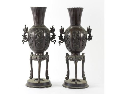 A pair of Chinese bronze vases, the globular panelled bodies with fluted and reeded necks on triform supports with circular b