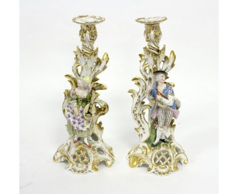 A pair of 19th Century Jacob Petit porcelain figural candlesticks, each modelled with musicians on gilded scrolling leaf supp