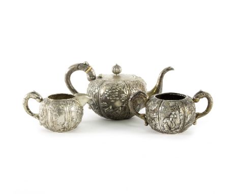 A Chinese silver coloured metal three-piece tea service, Cum Wo, Hong Kong, melon shape, embossed reserves of figures, dragon